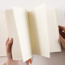 Person holding an open notebook with lined pages on a light background