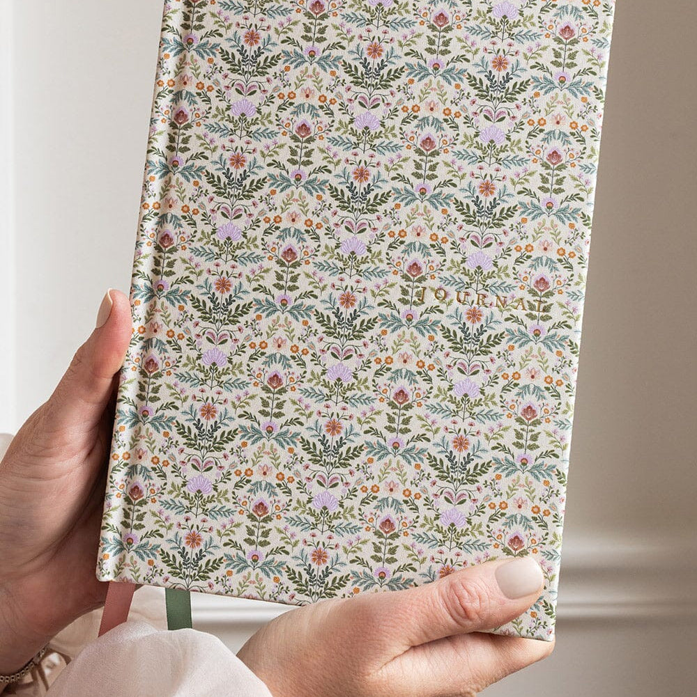 Floral patterned notebook held by a person against a neutral background
