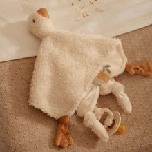 Plush toy goose with a pacifier on a textured surface