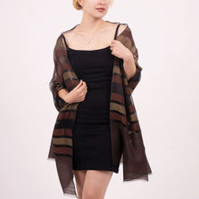Woman wearing a black dress with a brown striped cover-up on a white background