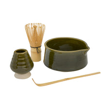 A green ceramic matcha set on a white background, including a small vase, a bamboo whisk, a large bowl, and a bamboo scoop.