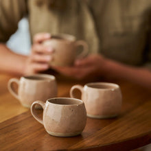 stoneware mugs with person holding mug in background