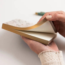 Person holding notepad with gold foiling on edge of pages