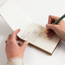 Person writing in a notebook with a pen on a white background