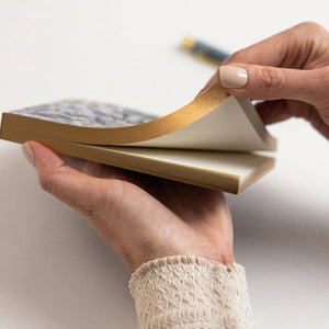 Person holding a notebook with a pen on a light background