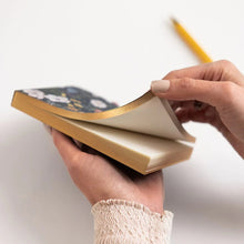 Person holding a notebook with a pencil on a white background