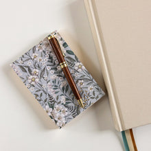 Floral notebook and pen on a light surface