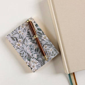 Floral notebook and pen on a light surface
