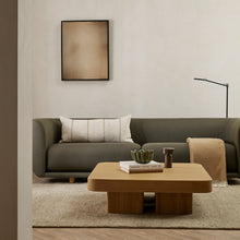 Modern living room with a gray sofa, wooden coffee table, and framed artwork on the wall.