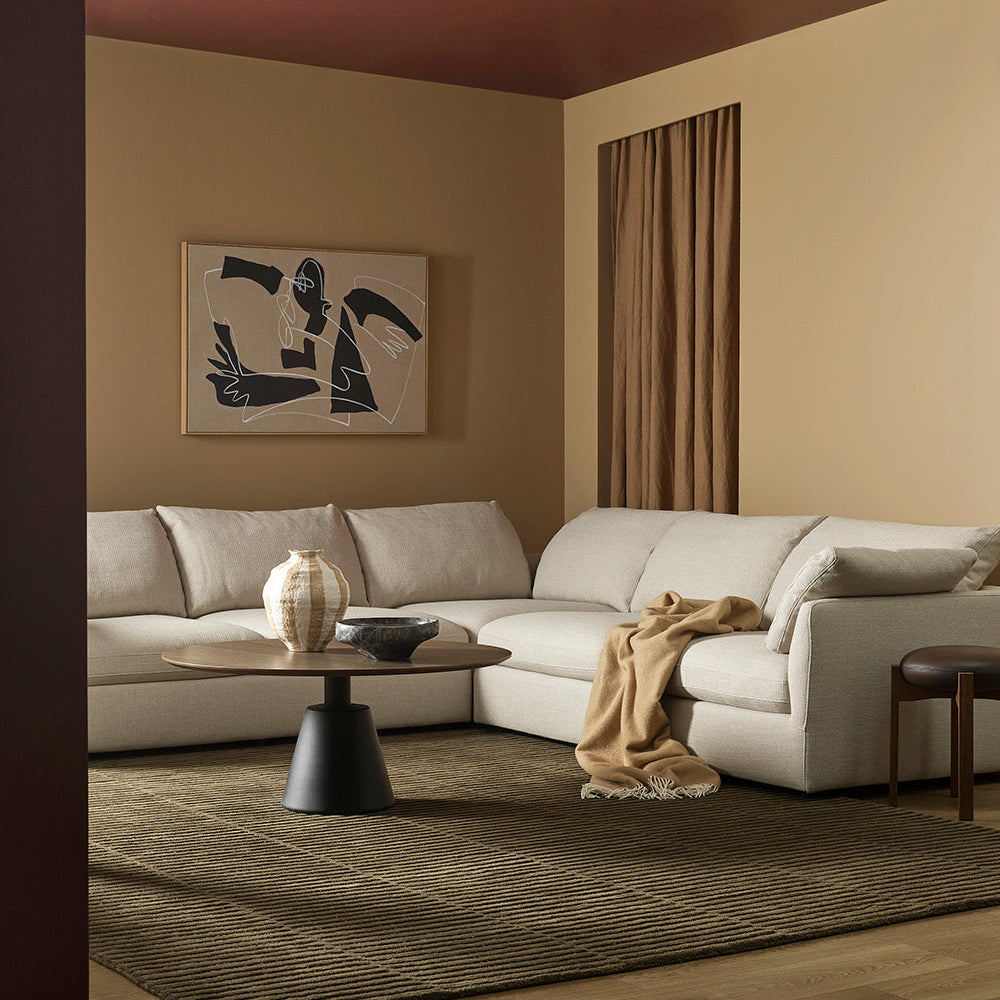 Modern living room with a sectional sofa, coffee table, and abstract art on the wall.
