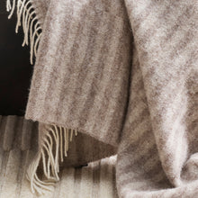 Close-up of a textured blanket with fringes on a dark background