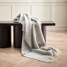 Gray blanket draped over a black bench against a neutral wall.