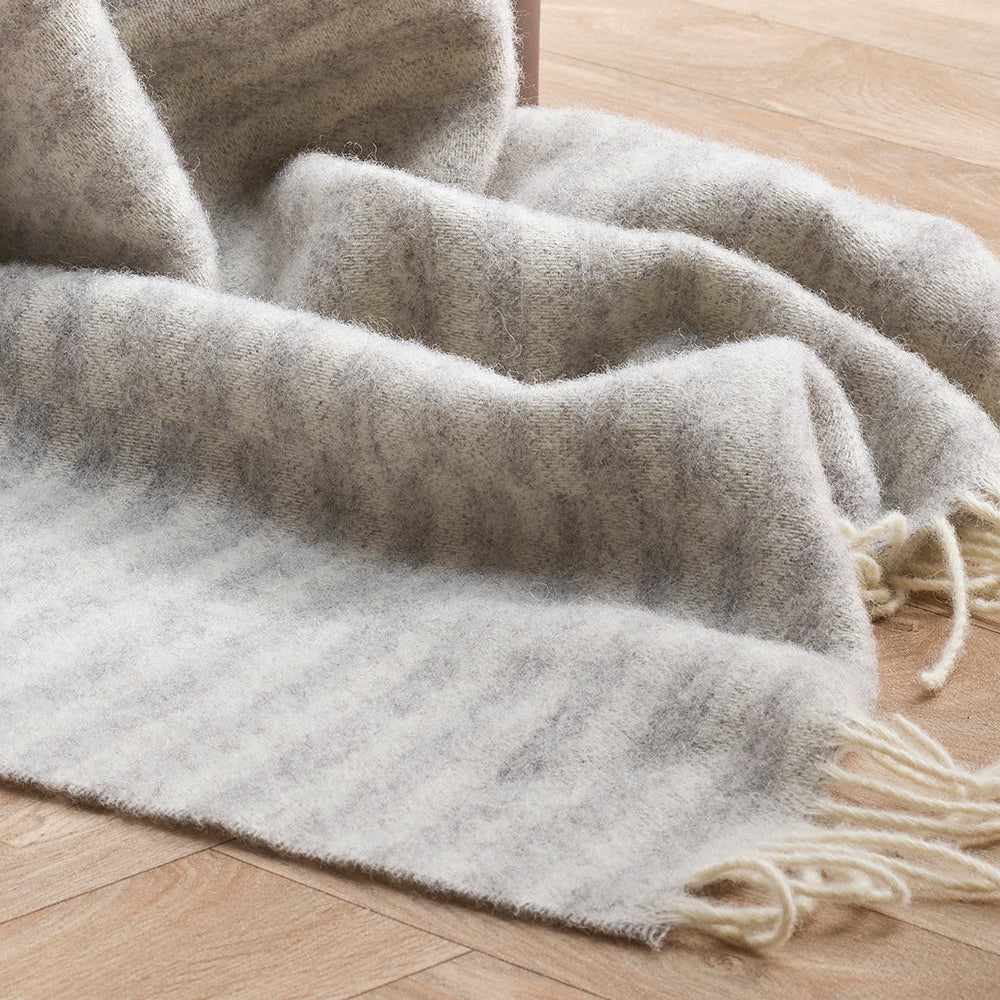 Gray blanket with tassels on a wooden floor