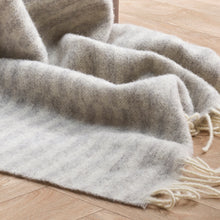 Gray blanket with tassels on a wooden floor