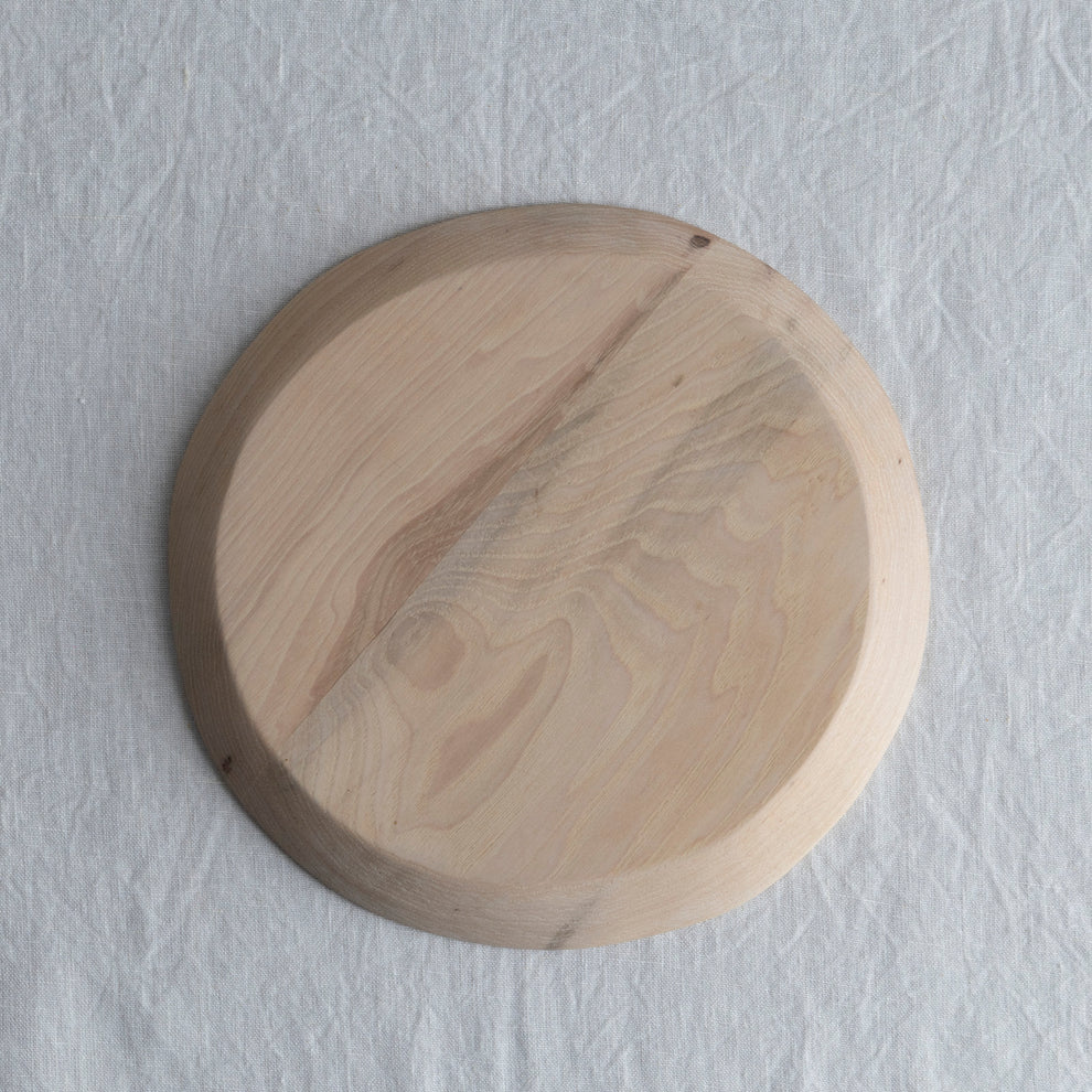 Round wooden cutting board on a light gray textured background