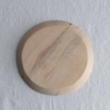 Round wooden cutting board on a light gray textured background