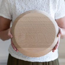 Person holding a round wooden board
