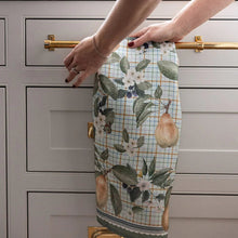 Person with floral and pear patterned tew towel in a kitchen setting