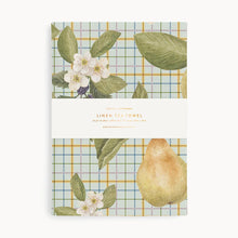 Packaging of a tea towel with plaid design and fruit illustration on a white background