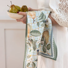 Person holding a bowl of pears with a decorative towel featuring fruit design.