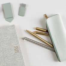 Stationery items including a notebook, pens, and a ruler on a white surface