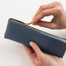 Hand holding a blue pencil case with 'bespoke letterpress' branding on a light background