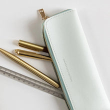 Light blue pencil case with gold pen and ruler on a white background
