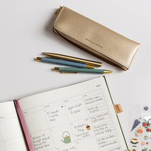 Open planner with pen and pencil case on a light gray background