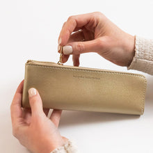 Gold pencil case held by hands on a light background
