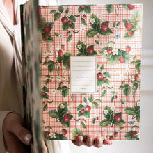 Person holding a notebook with a floral and checkered design