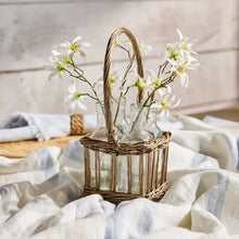 Decorative basket with glass bottles and white flowers on a light fabric background