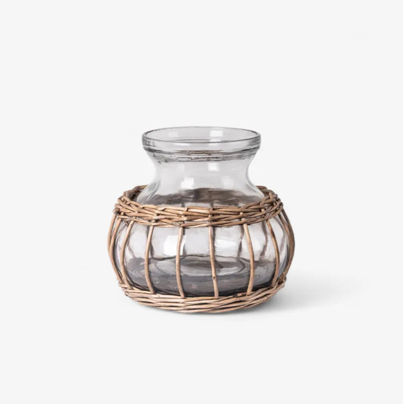 Glass vase with wicker basket base on a white background