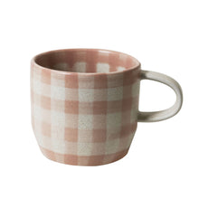 Checkered mug with a pink and beige pattern on a white background