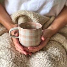 Person holding a checkered mug with a soft focus background