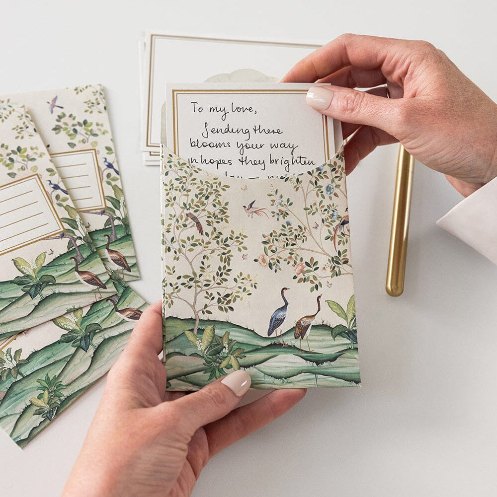 Two hands holding a card with nature-themed design and text on a white surface.