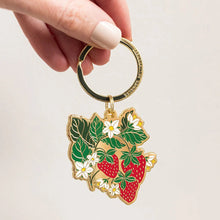 Keychain with strawberry design held by a hand on a light background