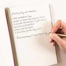 Hand writing in a journal with a pen on a white background