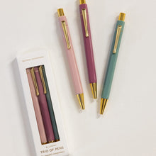 Three elegant pens in pastel pink, mauve, and sage green with gold accents, shown next to their white packaging box on a clean white background.
