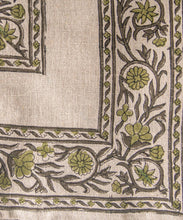 Close-up of a fabric with green floral patterns on a beige background
