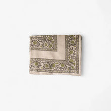 Folded fabric with intricate green patterns on a white background