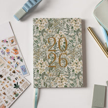 Floral notebook with '2026' design on a light surface with stationery items.