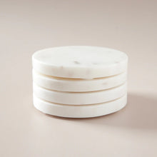 Stack of round white marble coasters on a beige background

