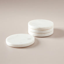 Set of white marble coasters on a beige background