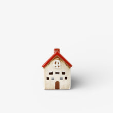 Small ceramic house figurine with a red roof on a white background