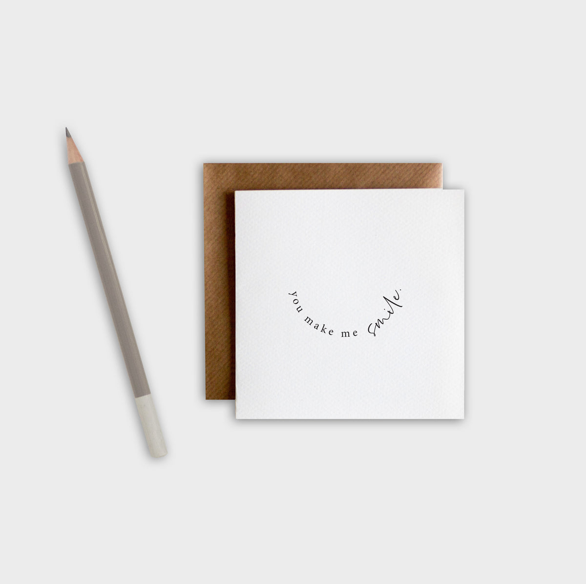 White card with brown envelope and pencil on white background
