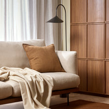 Cozy living room with beige sofa, brown pillow, and white blanket.